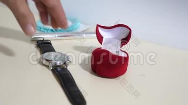 新郎准备用金戒指向他的新娘求婚。 人从<strong>桌子上拿起</strong>钟来度假。 特写